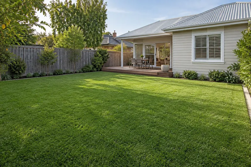 Enclosed backyard lawn beside a light-coloured home